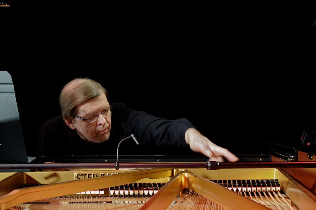 pianist playing the inside of a grand piano.