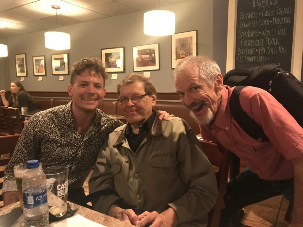 Three men seated at a restaurant posing for a photo