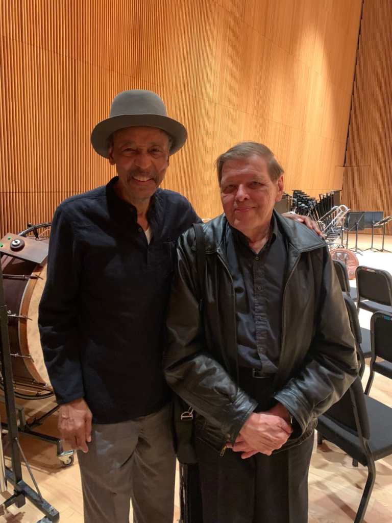 Two men posing for a photo in a concert hall