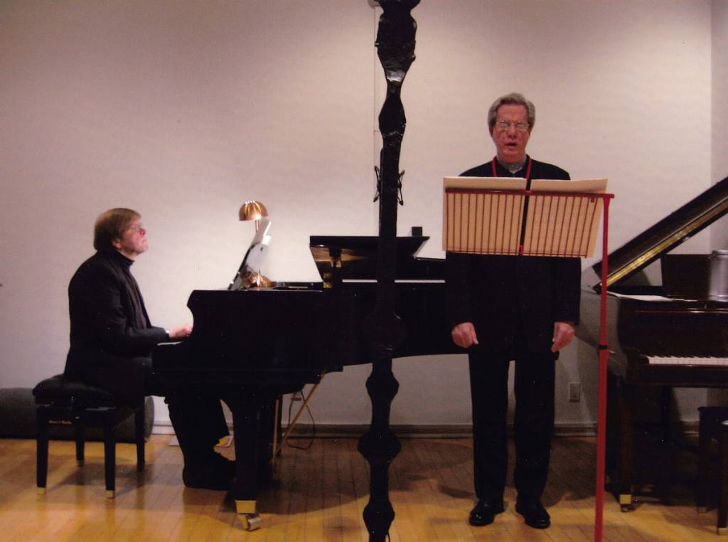 Two men performing; one singing, one playing the piano.