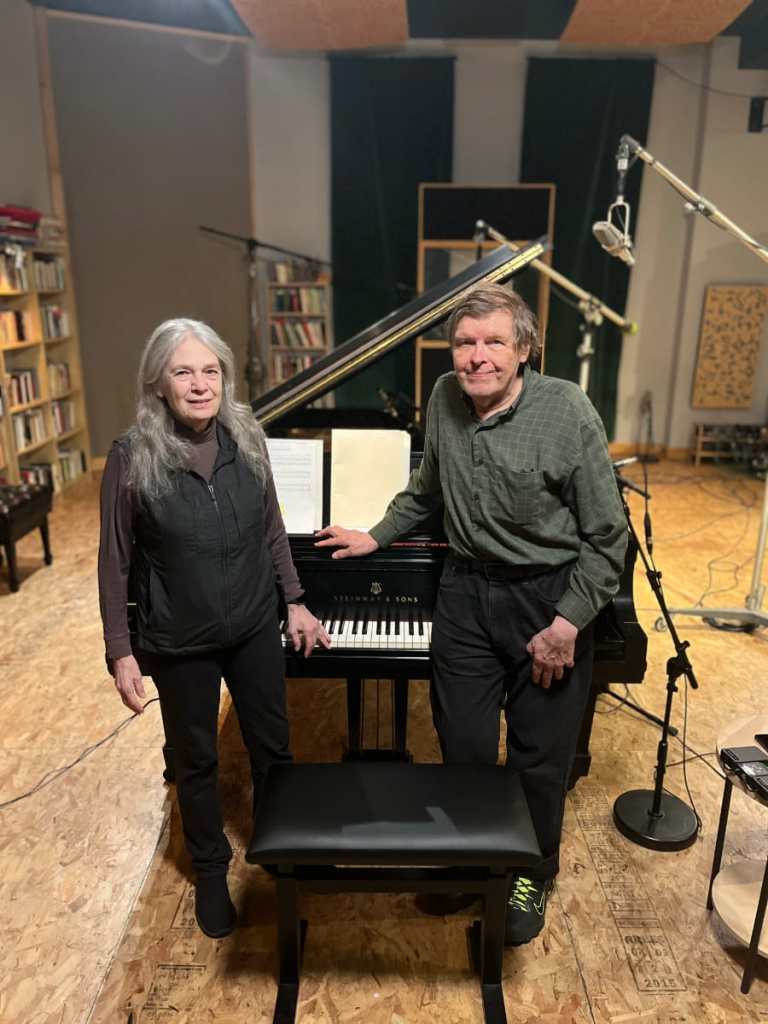 A woman and a man standing in front of a piano in a recording studio